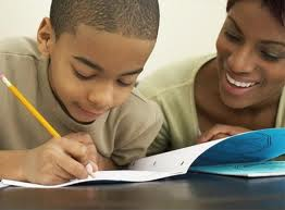 Kid Wrting in a Notebook with his parent next to him